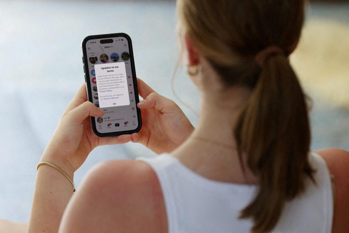 A teenager poses holding a mobile phone displaying a message from TikTok as law banning social media for users under 16 in Australia takes effect, in Sydney, Australia, December 10, 2025. REUTERS/Hollie Adams